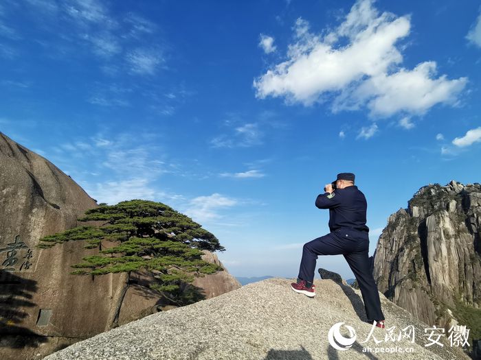 胡曉春手持望遠鏡,，正在查看迎客松冠頂情況,。 人民網(wǎng) 王銳攝